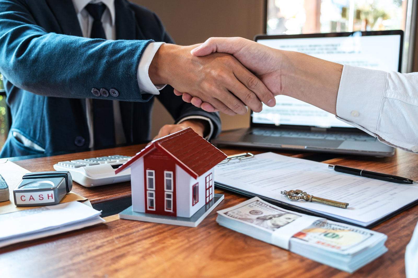 Business man and woman hands only doing a hand shake over desk.